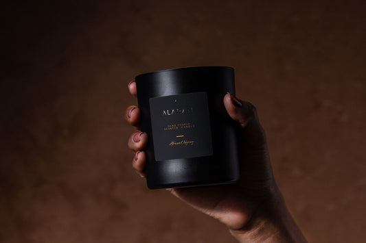 African Odyssey Candle being held up by a hand on a brown background